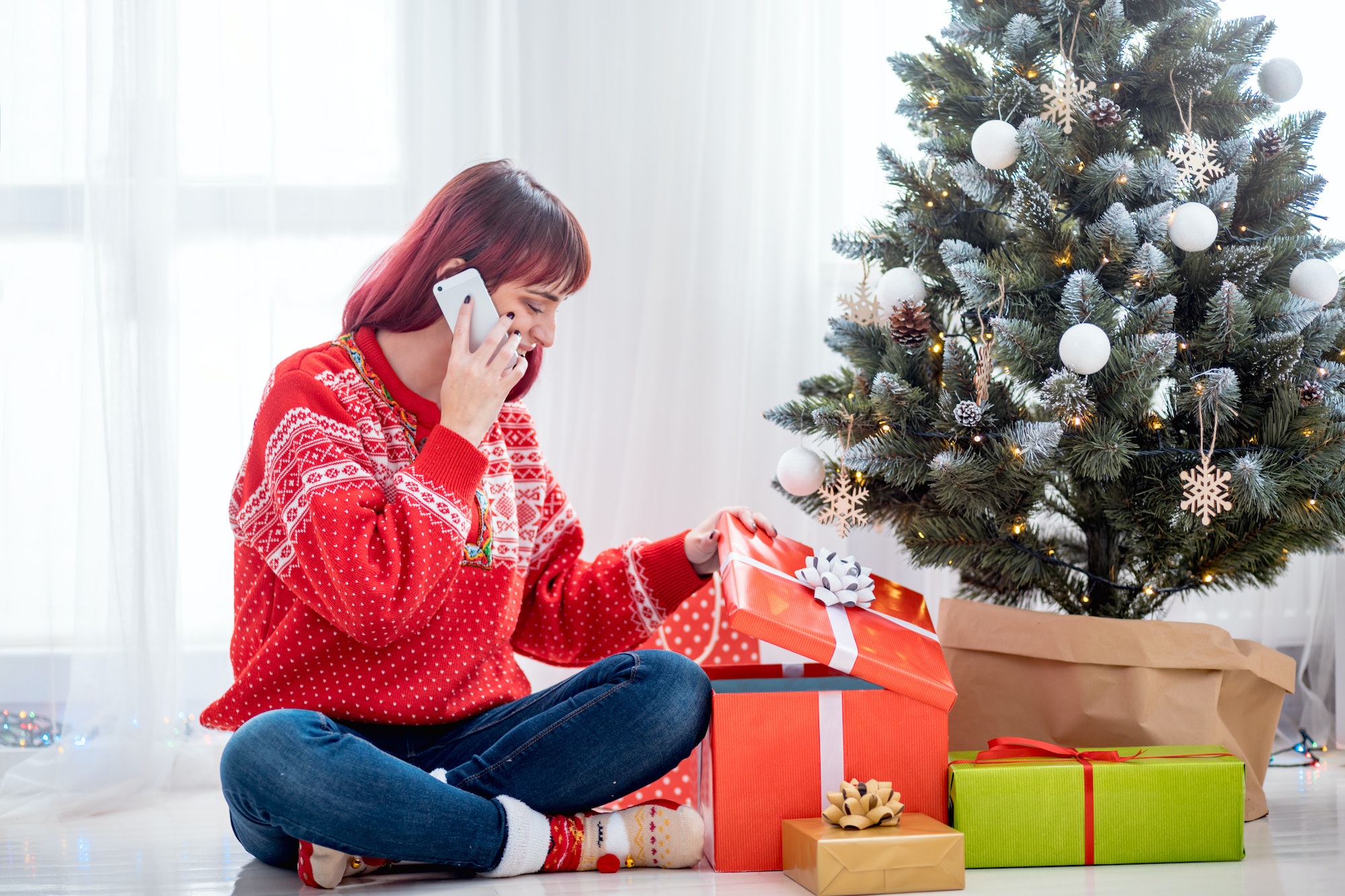 Young woman call mobile phone by Christmas tree